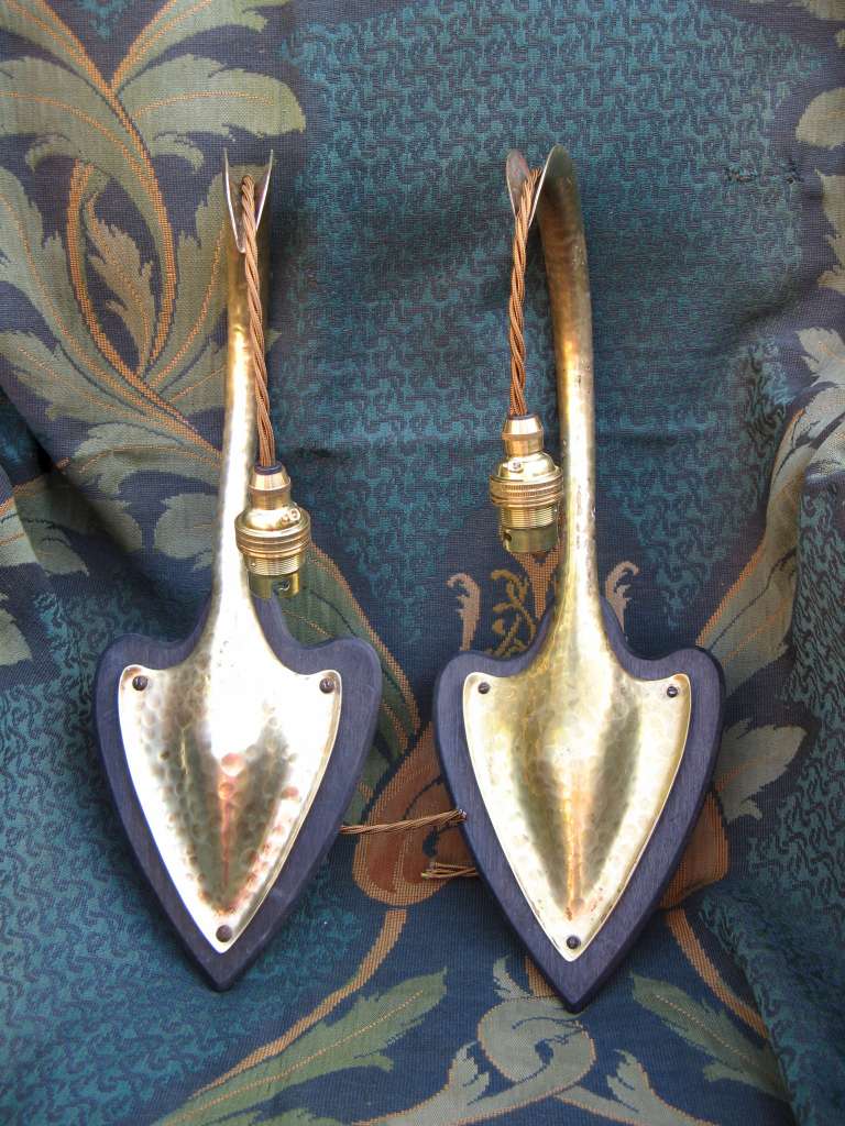 Pair of arts and crafts wall lights in hammered brass on wooden heart shaped backplates