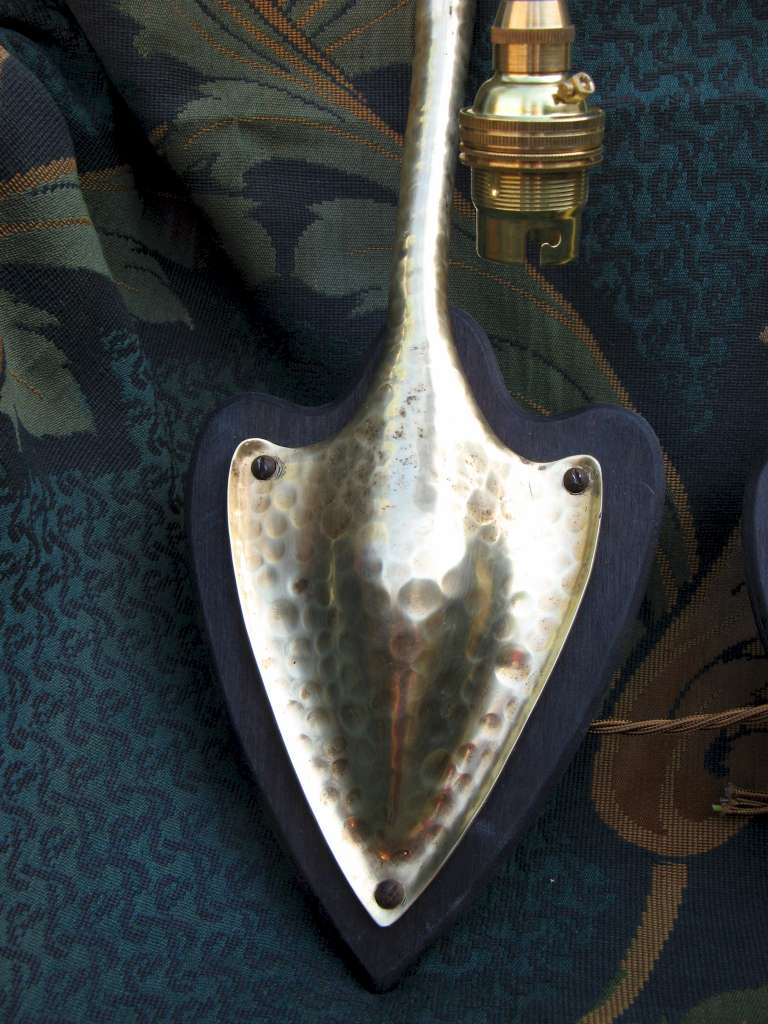 Pair of arts and crafts wall lights in hammered brass on wooden heart shaped backplates
