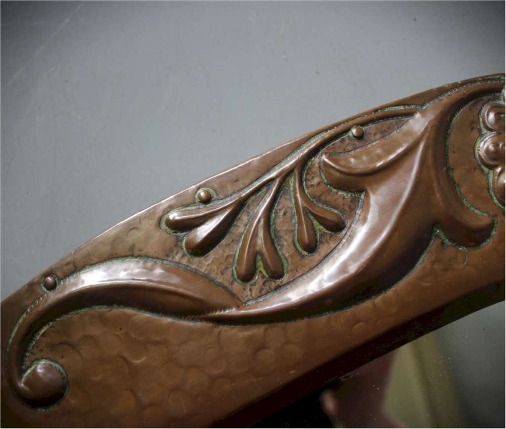 An Arts and Crafts copper oval wall mirror